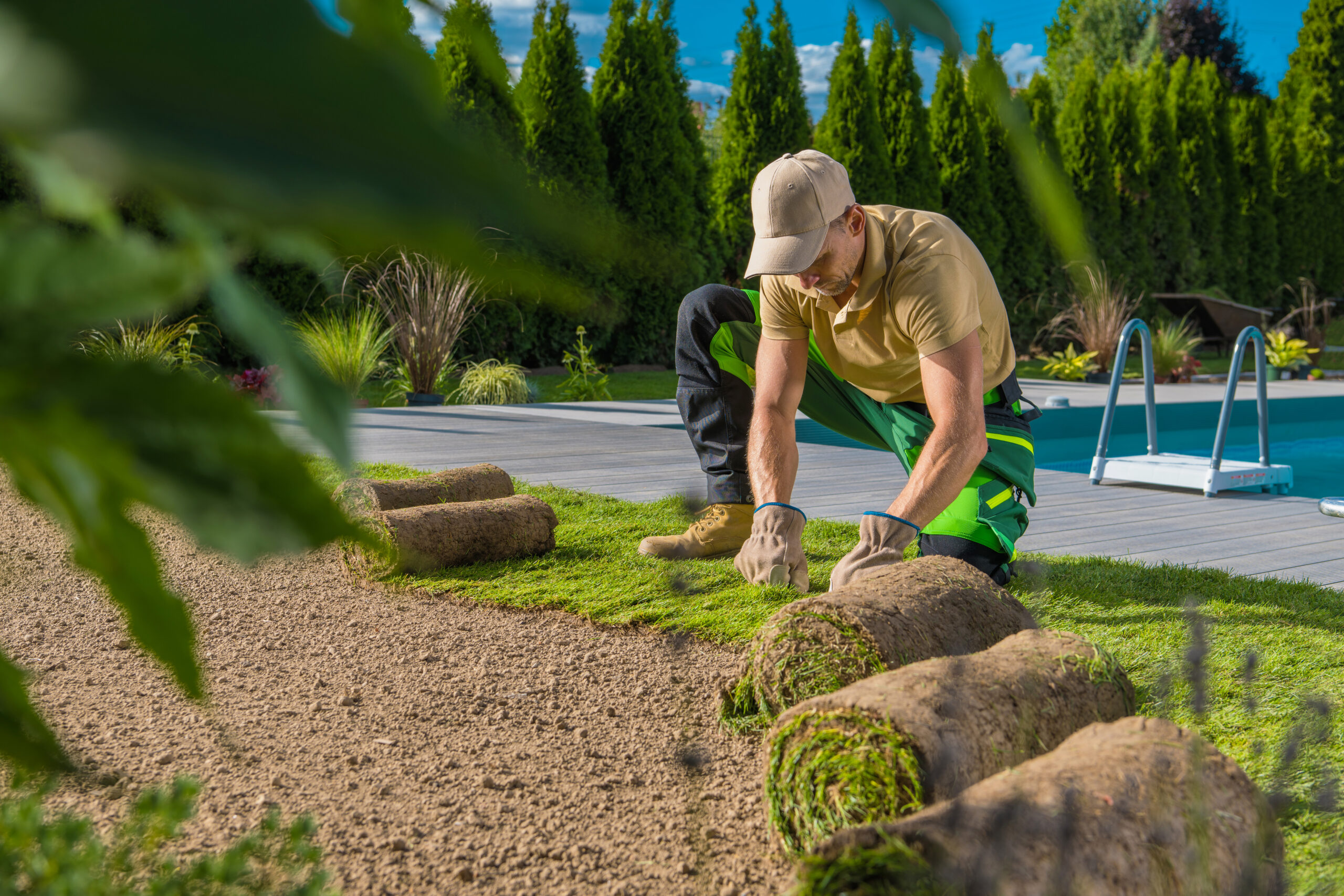 Rolls of Natural Grass Turfs Installed by Professional Landscaper. Building a Lawn Around the Swimming Pool.